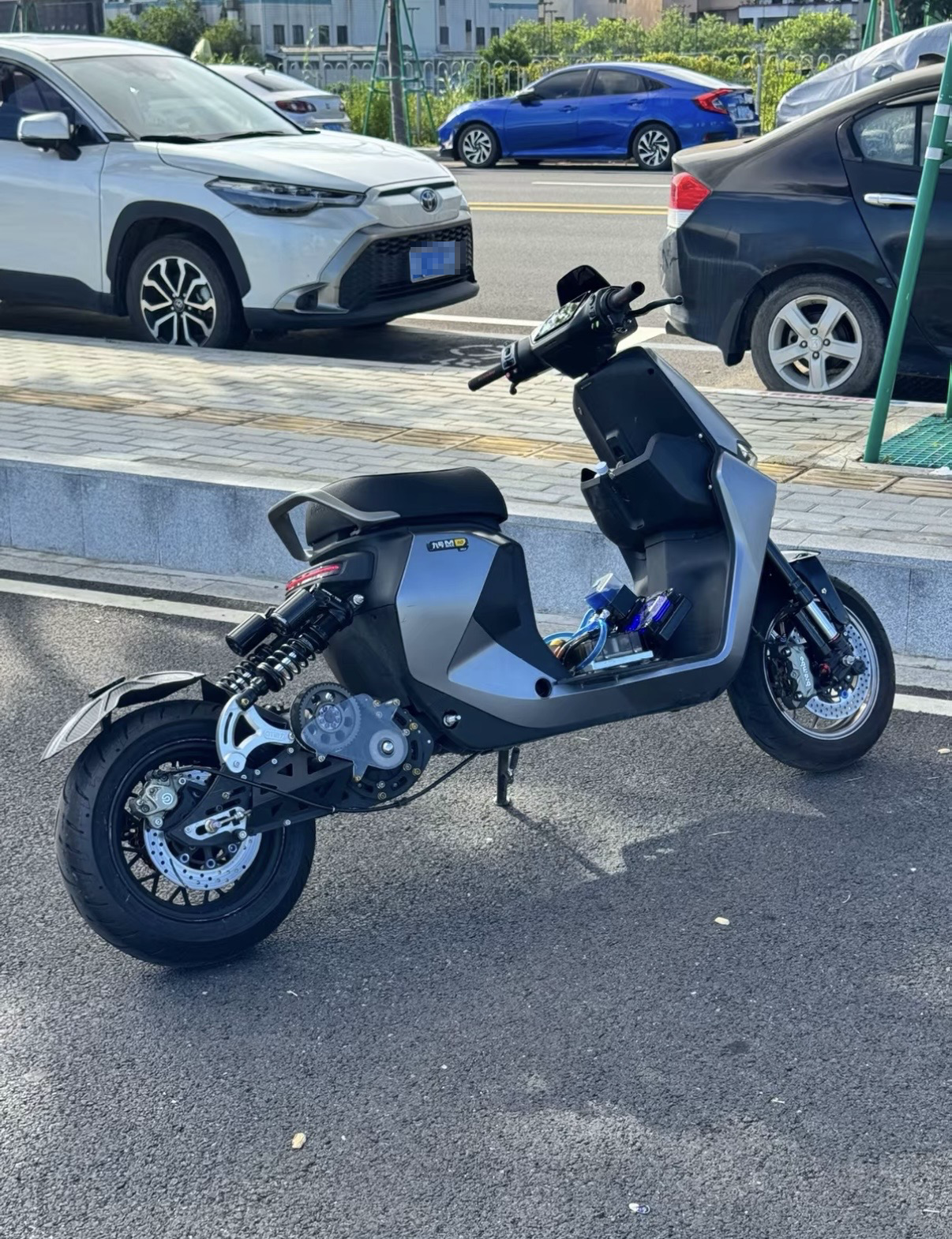 Street-side reference photograph of a customized Ninebot MMAX 110 electric motorcycle with a secondary-drive conversion