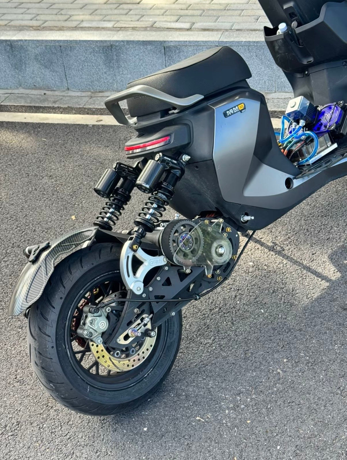 Close-up of the secondary-drive assembly and rear suspension on a customized Ninebot electric motorcycle